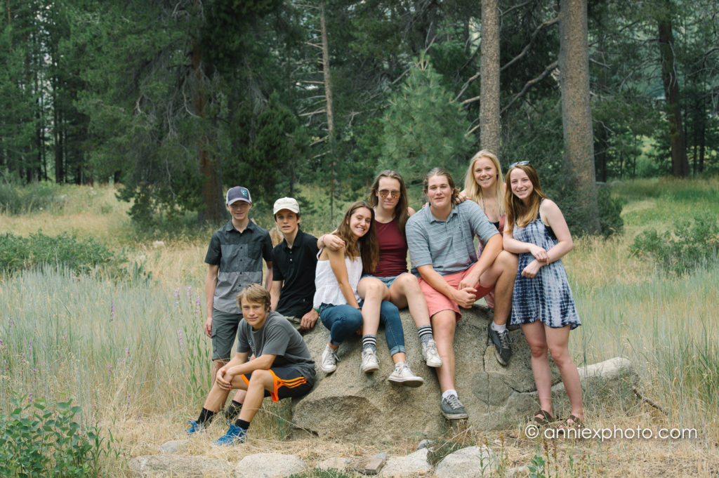 Group of youth skiers posing on a large boulder